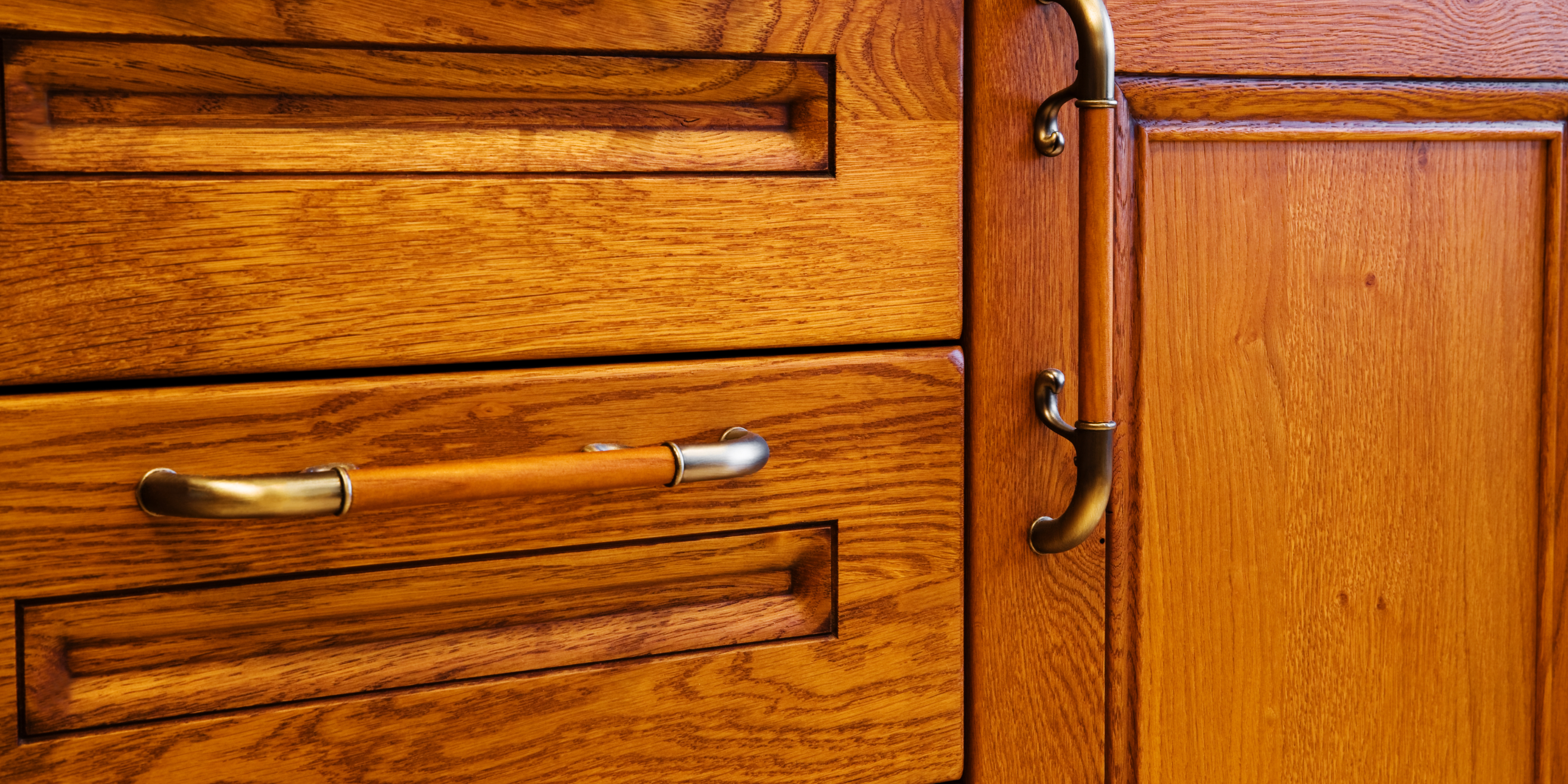 A close up picture of handles attached to wooden kitchen drawers and cupboards.